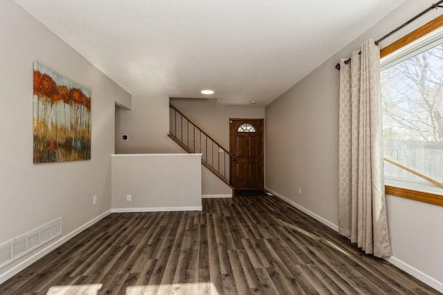 foyer entrance with dark wood-type flooring, visible vents, stairway, and baseboards