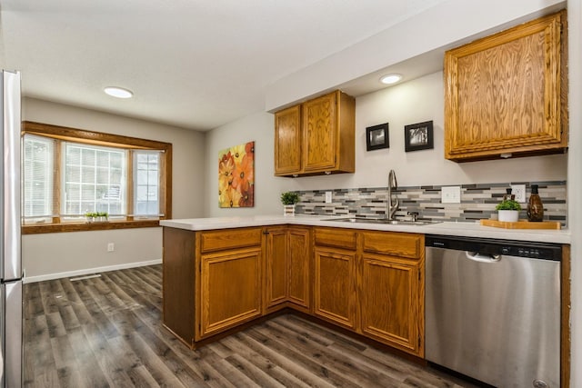 kitchen featuring dark wood-style flooring, a peninsula, light countertops, stainless steel dishwasher, and a sink