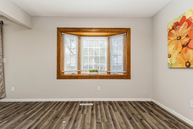 unfurnished room featuring dark wood-type flooring and baseboards