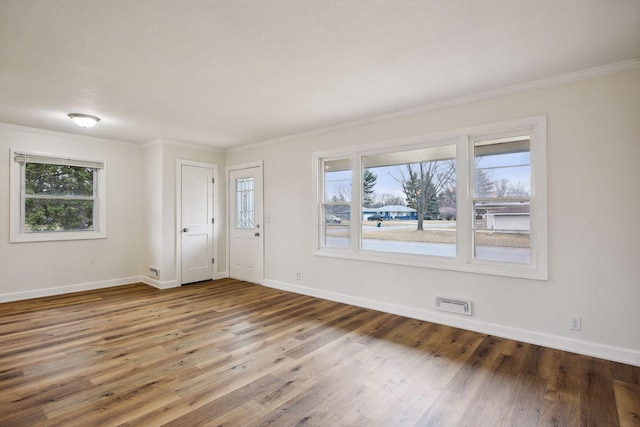 unfurnished room with wood finished floors, baseboards, a wealth of natural light, and ornamental molding