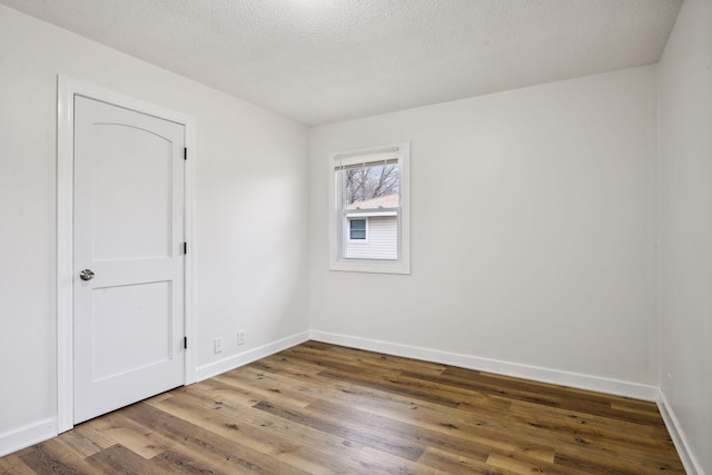 spare room with wood finished floors, baseboards, and a textured ceiling