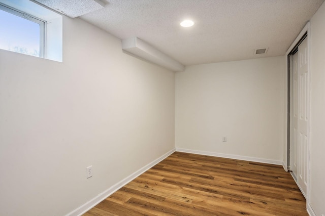 interior space featuring wood finished floors, visible vents, baseboards, a closet, and a textured ceiling