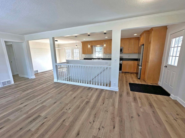 unfurnished living room with visible vents, a textured ceiling, light wood-style flooring, and crown molding