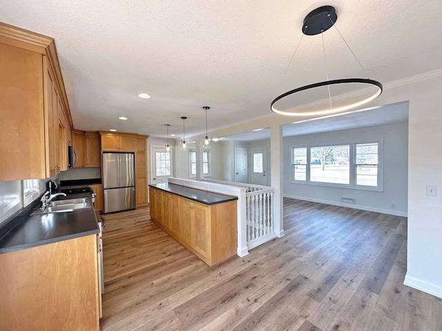 kitchen featuring dark countertops, light wood-type flooring, stainless steel appliances, a textured ceiling, and a sink