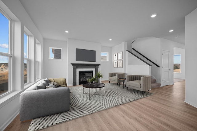 living room with stairway, wood finished floors, and a glass covered fireplace