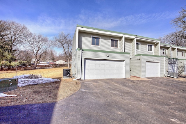 view of front of property with central air condition unit, driveway, and a garage