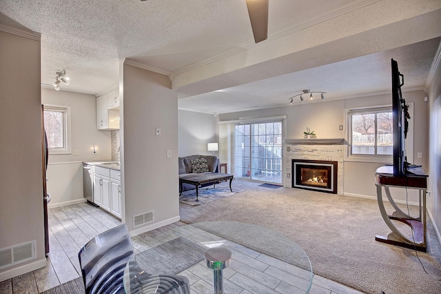 living room with light carpet, visible vents, a tiled fireplace, and a wealth of natural light