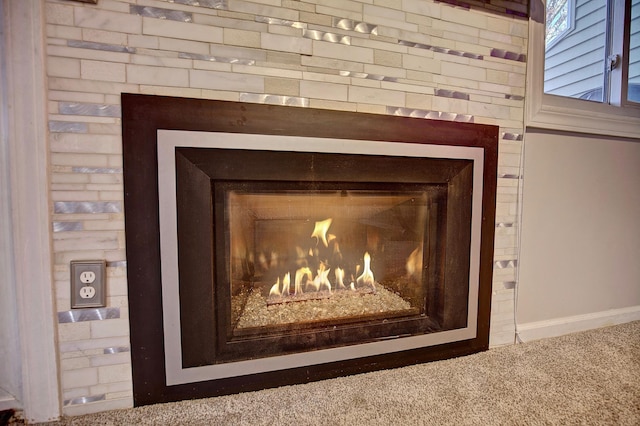 room details featuring baseboards, carpet floors, and a glass covered fireplace