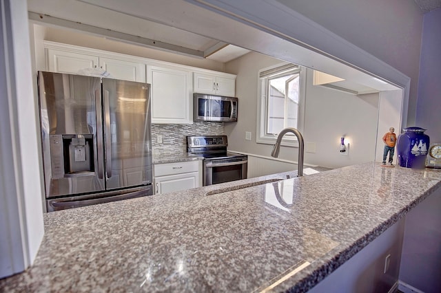 kitchen with backsplash, stone counters, stainless steel appliances, white cabinetry, and a sink