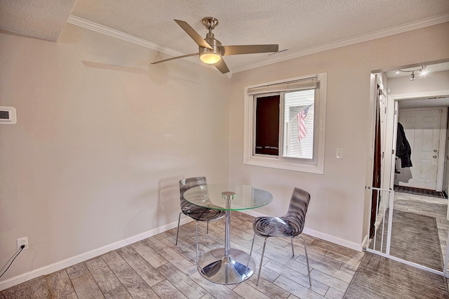 dining room featuring a textured ceiling, wood finished floors, baseboards, and ornamental molding