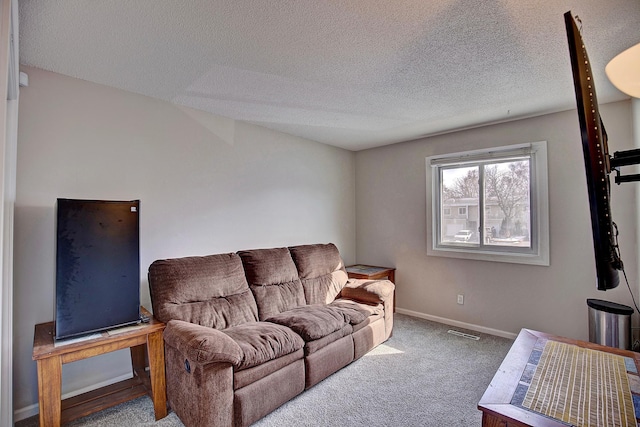 living area with visible vents, carpet flooring, a textured ceiling, and baseboards