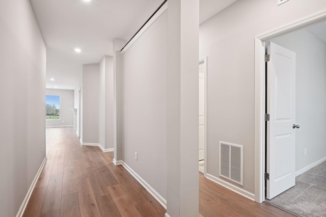 hallway featuring wood-type flooring, visible vents, baseboards, and recessed lighting