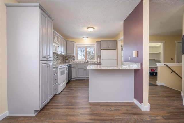 kitchen featuring a peninsula, white appliances, dark wood finished floors, and gray cabinetry