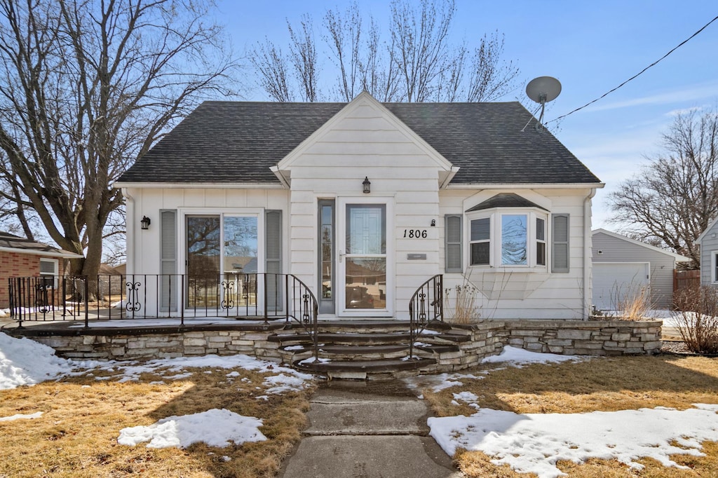 bungalow with a garage, an outbuilding, and roof with shingles