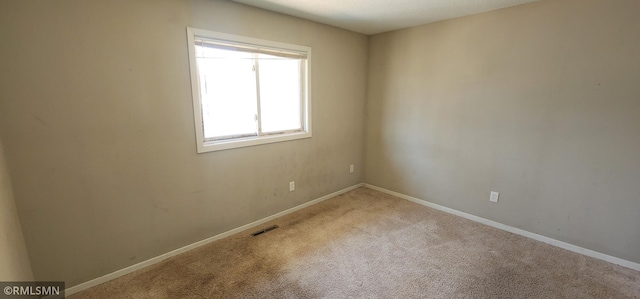 empty room featuring carpet, visible vents, and baseboards