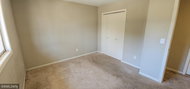 unfurnished bedroom with a closet, carpet floors, and baseboards