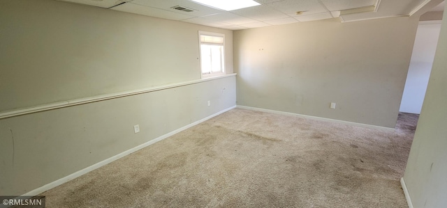 below grade area with a drop ceiling, visible vents, carpet floors, and baseboards