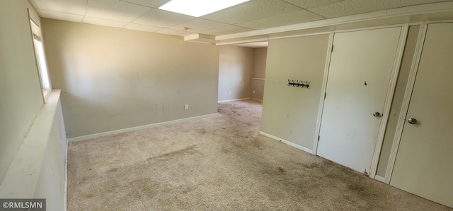 interior space with a drop ceiling, carpet floors, and baseboards