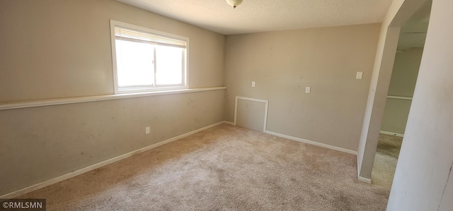 spare room featuring baseboards, carpet floors, and a textured ceiling