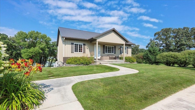 view of front of property featuring covered porch, metal roof, and a front lawn