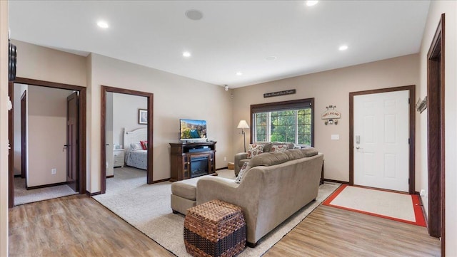 living area with recessed lighting, light wood-style flooring, a fireplace, and baseboards