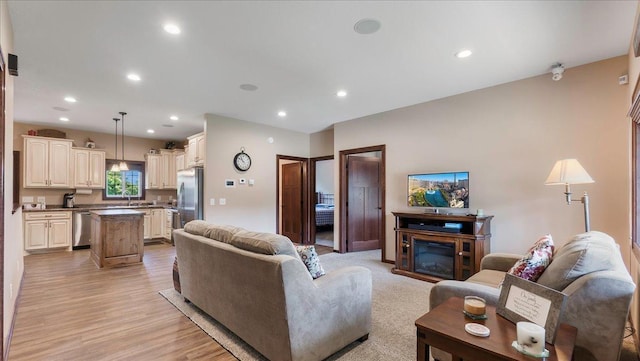 living room featuring a glass covered fireplace, recessed lighting, and light wood-style floors