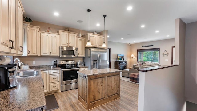 kitchen with light wood-type flooring, a sink, a kitchen island, open floor plan, and appliances with stainless steel finishes