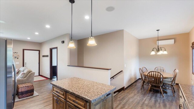 kitchen featuring light wood-type flooring, a wall unit AC, recessed lighting, freestanding refrigerator, and a chandelier