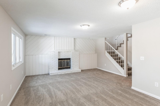 unfurnished living room featuring carpet, a brick fireplace, a textured ceiling, and stairs