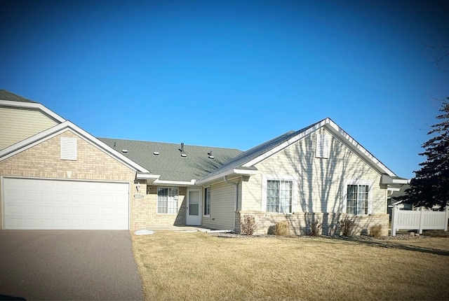 view of front of house with driveway, fence, a front yard, a garage, and brick siding