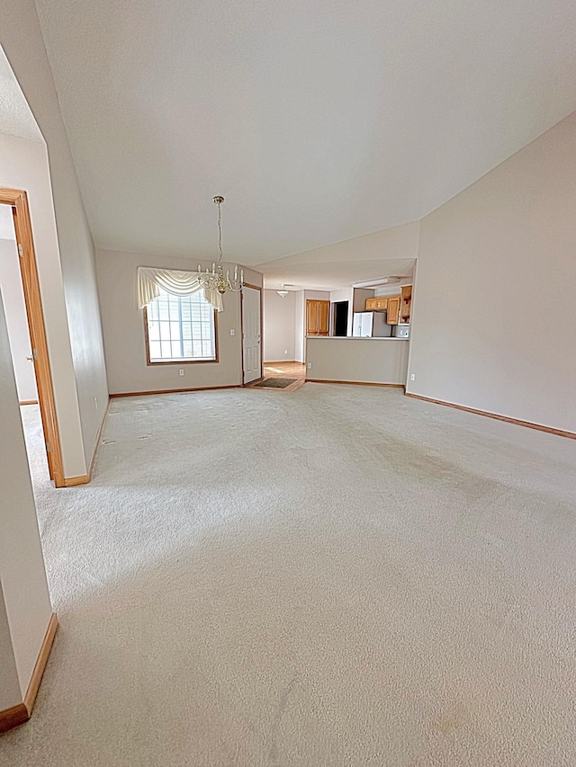 unfurnished living room featuring a notable chandelier, carpet flooring, and baseboards