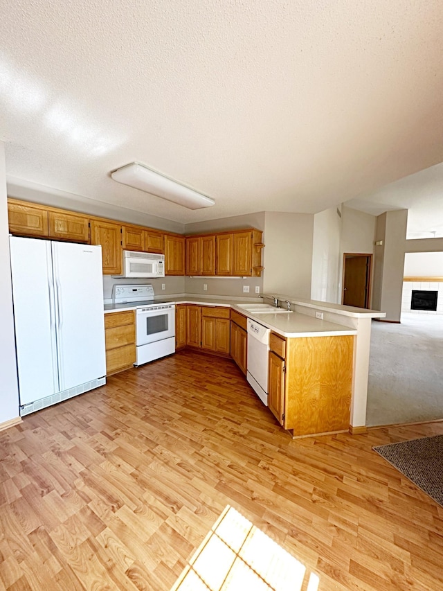 kitchen featuring open floor plan, light countertops, a peninsula, light wood-style floors, and white appliances