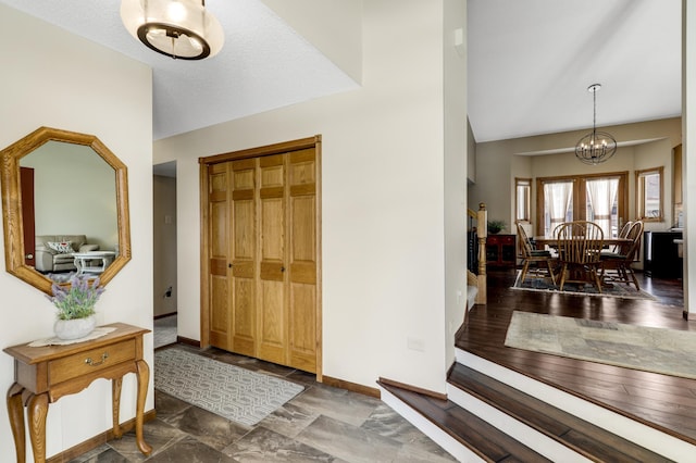 entryway with lofted ceiling, an inviting chandelier, baseboards, and a textured ceiling