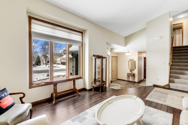 interior space with hardwood / wood-style flooring, vaulted ceiling, baseboards, and stairs