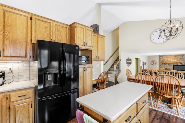 kitchen featuring dark wood finished floors, decorative backsplash, vaulted ceiling, black refrigerator with ice dispenser, and light countertops