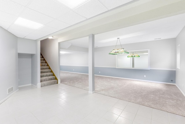 finished basement with carpet, visible vents, stairway, a drop ceiling, and baseboards