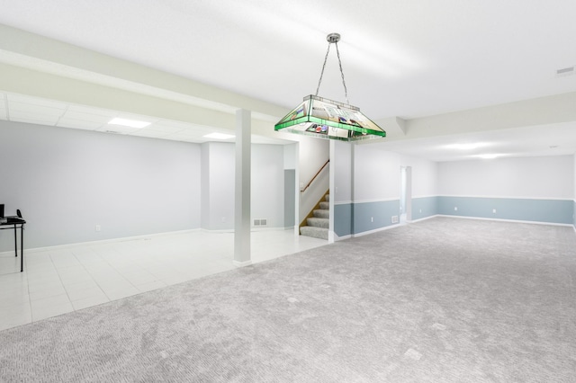 finished below grade area with visible vents, a paneled ceiling, tile patterned floors, stairs, and carpet floors