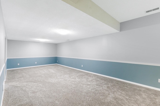 unfurnished room featuring a textured ceiling, carpet floors, visible vents, and baseboards