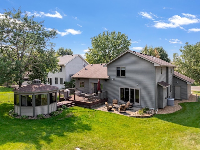 back of property featuring a fire pit, a lawn, cooling unit, a wooden deck, and a patio area