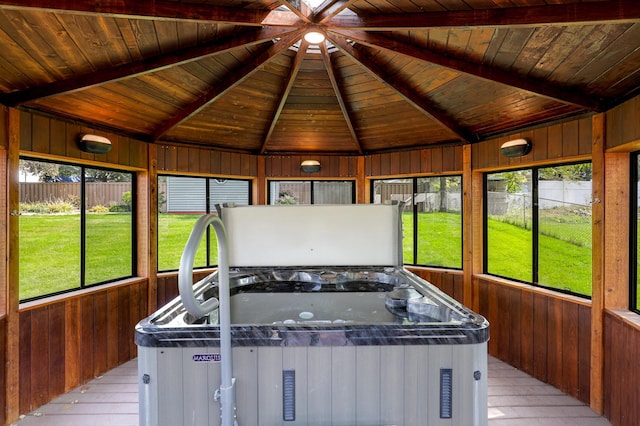 unfurnished sunroom featuring vaulted ceiling with beams, wood ceiling, a healthy amount of sunlight, and a jacuzzi