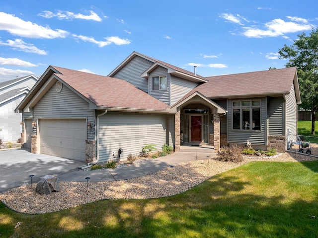 split level home with an attached garage, driveway, stone siding, roof with shingles, and a front yard