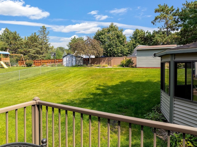 view of yard featuring a playground, a shed, an outdoor structure, and a fenced backyard