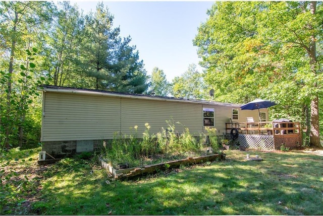 back of property with a lawn, a wooden deck, and a garden