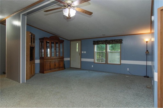 carpeted spare room with lofted ceiling, ornamental molding, and a ceiling fan