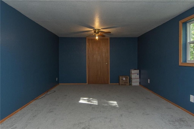 carpeted empty room featuring ceiling fan and baseboards