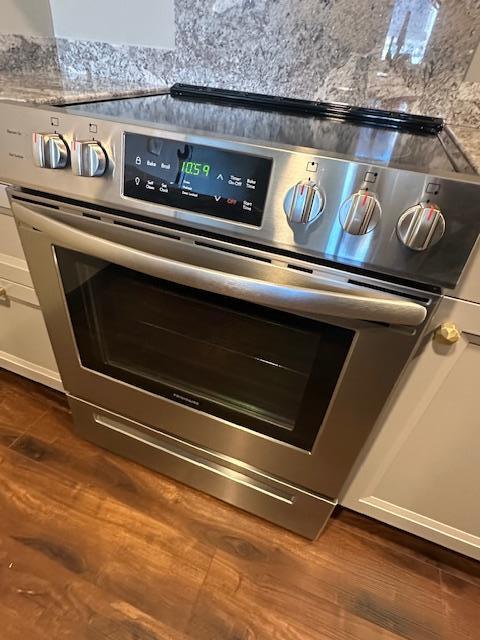 room details featuring stainless steel electric range and dark wood finished floors