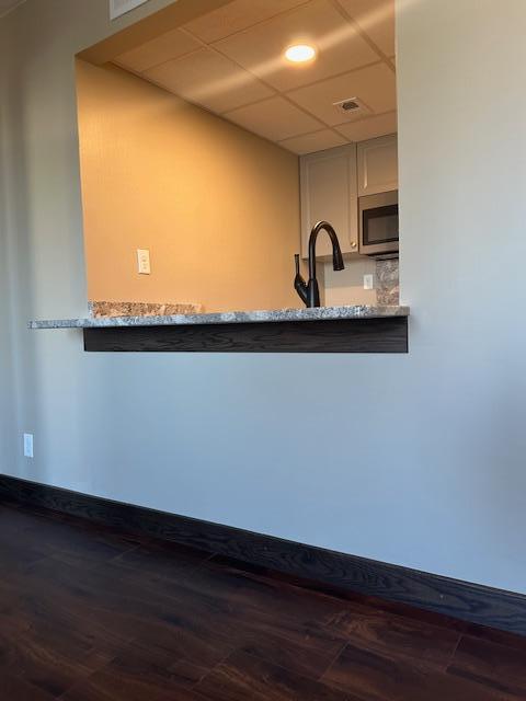 kitchen with a paneled ceiling, stainless steel microwave, visible vents, a sink, and baseboards