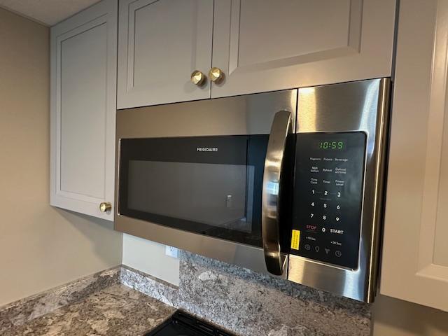 room details featuring white cabinetry and stainless steel microwave