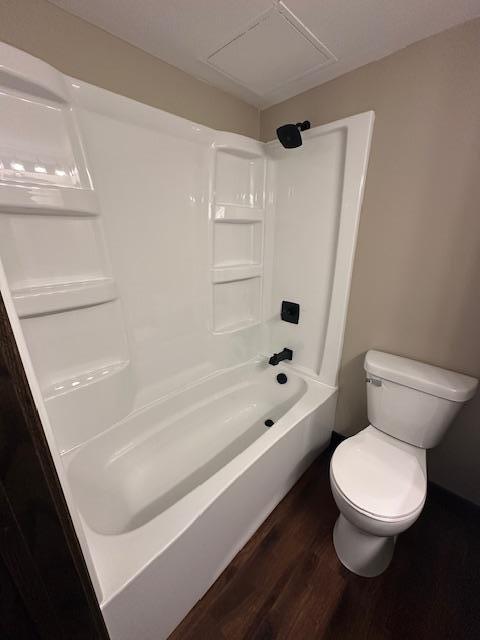 bathroom featuring  shower combination, toilet, and wood finished floors