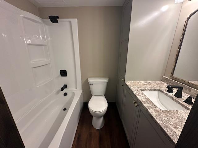 full bathroom featuring wood finished floors, shower / washtub combination, vanity, and toilet